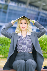 The businesswoman is holding a laptop on her head. The woman has hidden herself. Concept.