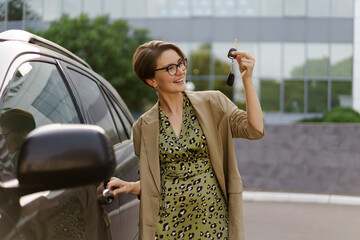 Pretty woman with short haircut posing near luzury car. autumn mood. Wearing stylish casual outfit.