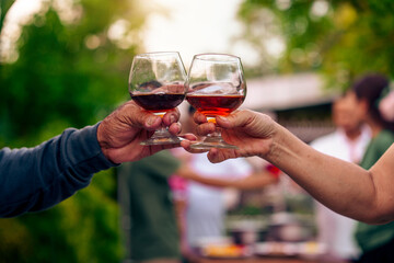 Home Garden BBQ Party, Wine Glasses Clink in Family Toast, enjoying harvest time together outside at front of house, grandfather and grandfather asian people, man and woman