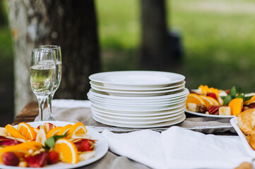A round fruit plate, champagne glasses, empty dishes stand on a wooden table at a banquet. Photo of food, dessert, buffet at the holiday.