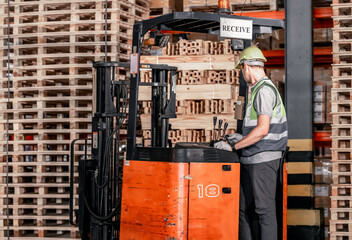 Fototapeta na wymiar Warehouse forklift operator moves, stores merchandise, stays in touch with team, boss via radio