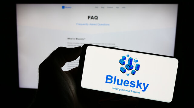 Stuttgart, Germany - 09-02-2023: Person holding cellphone with logo of social network initiative Bluesky on screen in front of webpage. Focus on phone display.