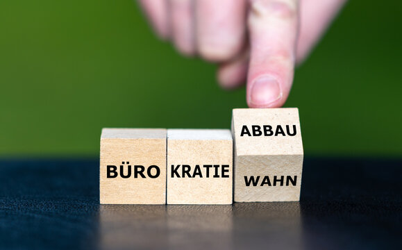 Hand dreht W&uuml;rfel und &auml;ndert den Ausdruck B&uuml;rokratiewahn in B&uuml;rokratieabbau. 