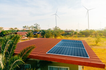 Solar cells are on the roof of the house and wind turbines in the background. renewable energy....