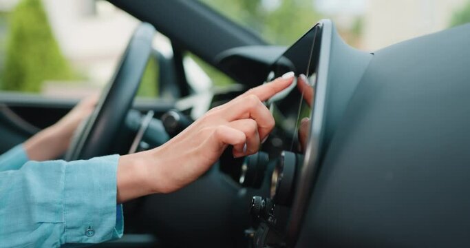 Close up shot hand of woman using touch screen in car setting up the navigation gps application on the touchscreen console.
