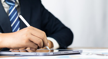 Electronic signature concept, Paperless office concept. Businessman uses a pen to sign electronic...