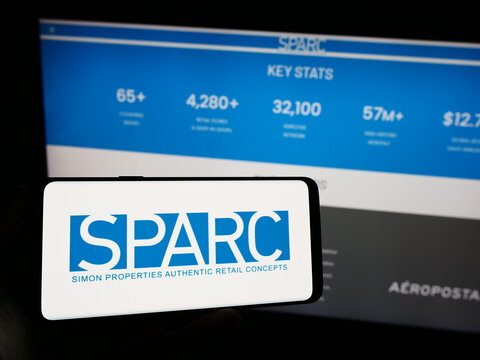 Stuttgart, Germany - 09-02-2023: Person holding mobile phone with logo of American retail company SPARC Group LLC on screen in front of web page. Focus on phone display.