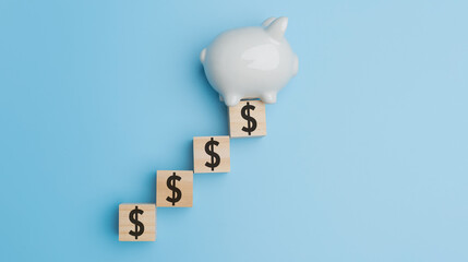 Top view, Flat lay the white piggy bank with USD dollar on wood of cube on blue background with copy space. Financial, Accounting, banking, investment, saving money concept.