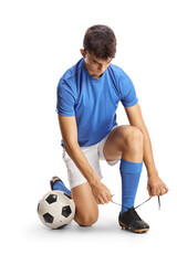 Full length shot of a footballer kneeling and tying cleats