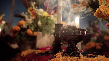 A copal goblet is burning on a grave during day of the dead celebration.