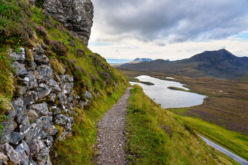 Green mountain landscape with trail to the lake found in the valley, Scotland, UK.