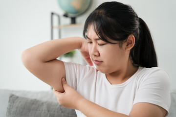 Close up of Chubby woman pinching upper arm fat. weight loss concept.