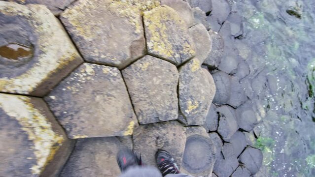 POV of man shoes walking on Giants Causeway Ireland 