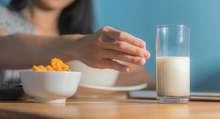 healthy woman eating corn flakes cereal while sitting and having breakfast at the kitchen table