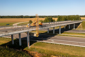 Drone photography of construction workers with a crane inspecting and repairing a bridge