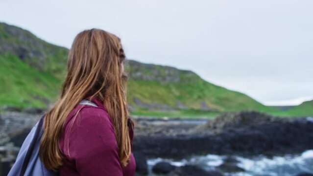 Woman looking out at ocean in Ireland Giant's Causeway. Close up with smile