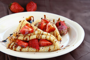 thin pancakes with fresh strawberries and chocolate sauce