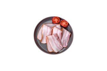 Delicious fresh raw bacon cut with slices on a grey plate against a dark concrete background