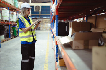 Distribution warehouse worker using digital tablet checking inventory storage on shelf. Female merchandise supervisor, logistic engineer working at storage room in storehouse. Goods supply management