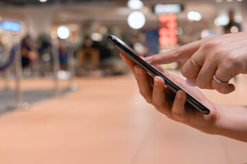 Close-up young woman using finger point on screen mobile phone to online shopping, hipster touch black screen on smartphone light night city, person texting message, online internet