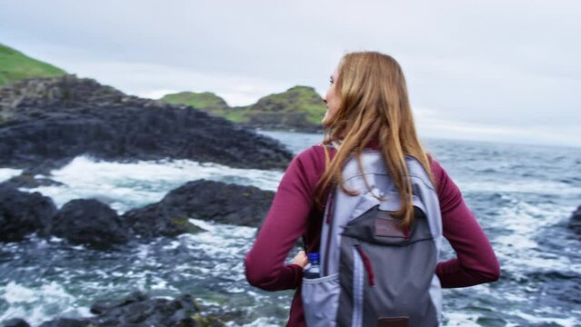 Giant's causeway waves crashing with woman looking out with a smile