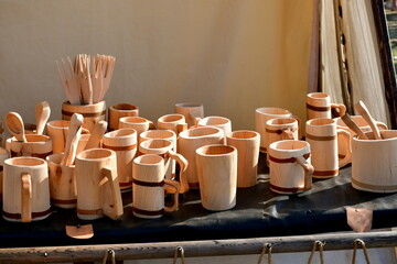 A close up on a number of wooden bowls, vases, mugs, cups, and other kitchen utensils displayed on...