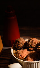 fried chicken with ketchup and mustard in a yellow terracotta bow with star anise on an old wooden table