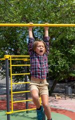 Fototapeta premium Boy hanging from an exercise bar screaming