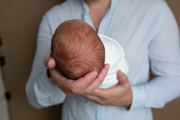 child's head in father's hands. paternal feelings. small newborn head