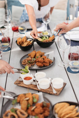 hands reaching to pick up food on a table together