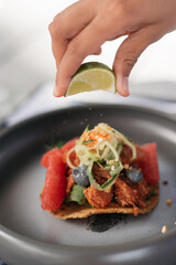 chef preparing gourmet taco on a plate with lime