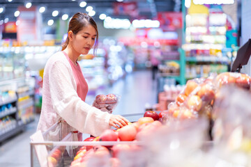 Asian woman who is four months pregnant. Choosing food meticulously in the supermarket