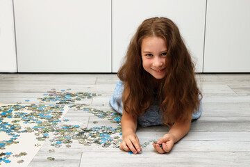 girl collects a puzzle from small pieces