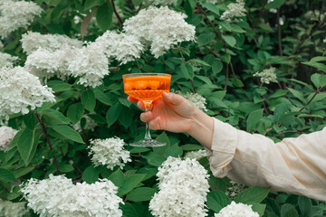 Female hand holding Aperol spritz cocktails outdoors, focus on hands