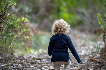 blonde todder walking in a forest on a hike in spring