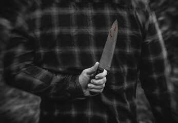 A man with a bloody knife in his hand close up.