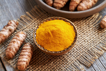 Curcuma powder and fresh turmeric root on a table