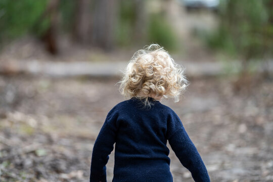 blonde todder walking in a forest on a hike in spring
