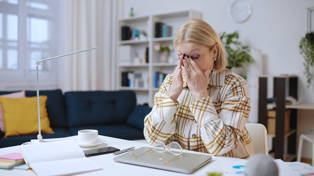 Tired businesswoman in her 50s getting bad news at work, feeling exhausted