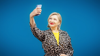 A senior female influencer is taking a selfie on her phone as part of a social media challenge