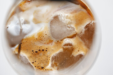 Texture Iced espresso coffee to wineglass with ice, top view, hard light