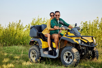 Portrait of a smiling love couple on a rental quad bike during an off-road ride.