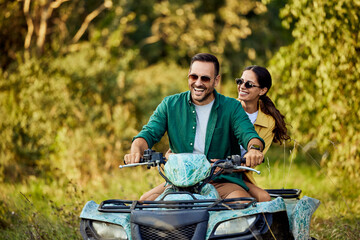 A happy love couple having fun while driving a quad bike through nature. © bnenin