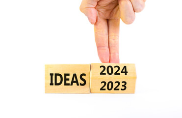 2024 ideas new year symbol. Businessman turns a wooden cube and changes words Ideas 2023 to Ideas 2024. Beautiful white background, copy space. Business 2024 ideas new year concept.