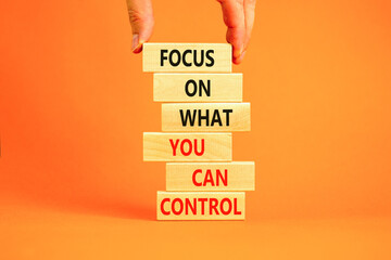 Focus on control symbol. Concept words Focus on what you can control on wooden block. Beautiful orange table orange background. Businessman hand. Business control motivational never stress concept.