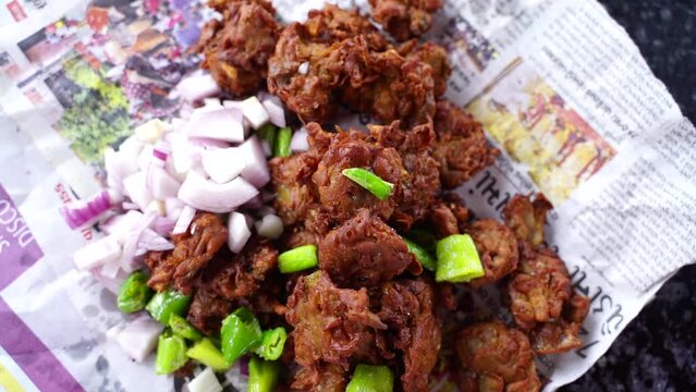 Tasty pakode with fried chilly and onion, served in Gujarati newspaper Indian street food called tikadi.