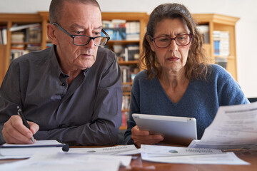 Senior couple with with tablet managing bills and paperwork. Small business accounting