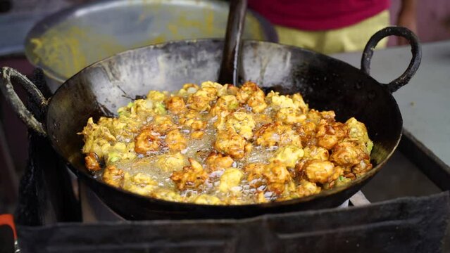 A close-up scene of frying crispy tikadi called flitter and pakoda Indian street food, onion pakora specially for rainy season with blur background.