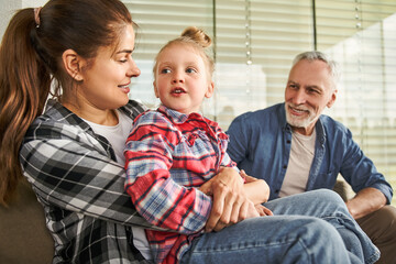 Obraz premium Cheerful grandfather looking at the little kid girl while spending time with family
