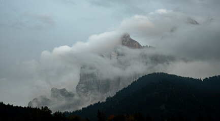 Cloudy fogy sky mountain peaks covered in mist in the morning. Dolomite rocky mountains Italy